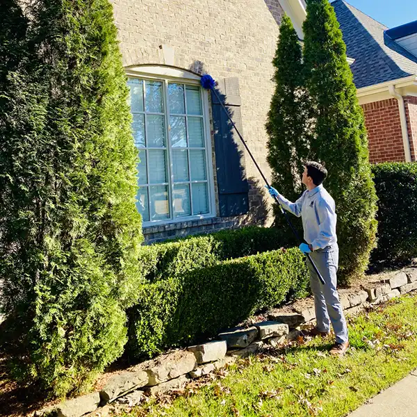 worker cleaning window outside home